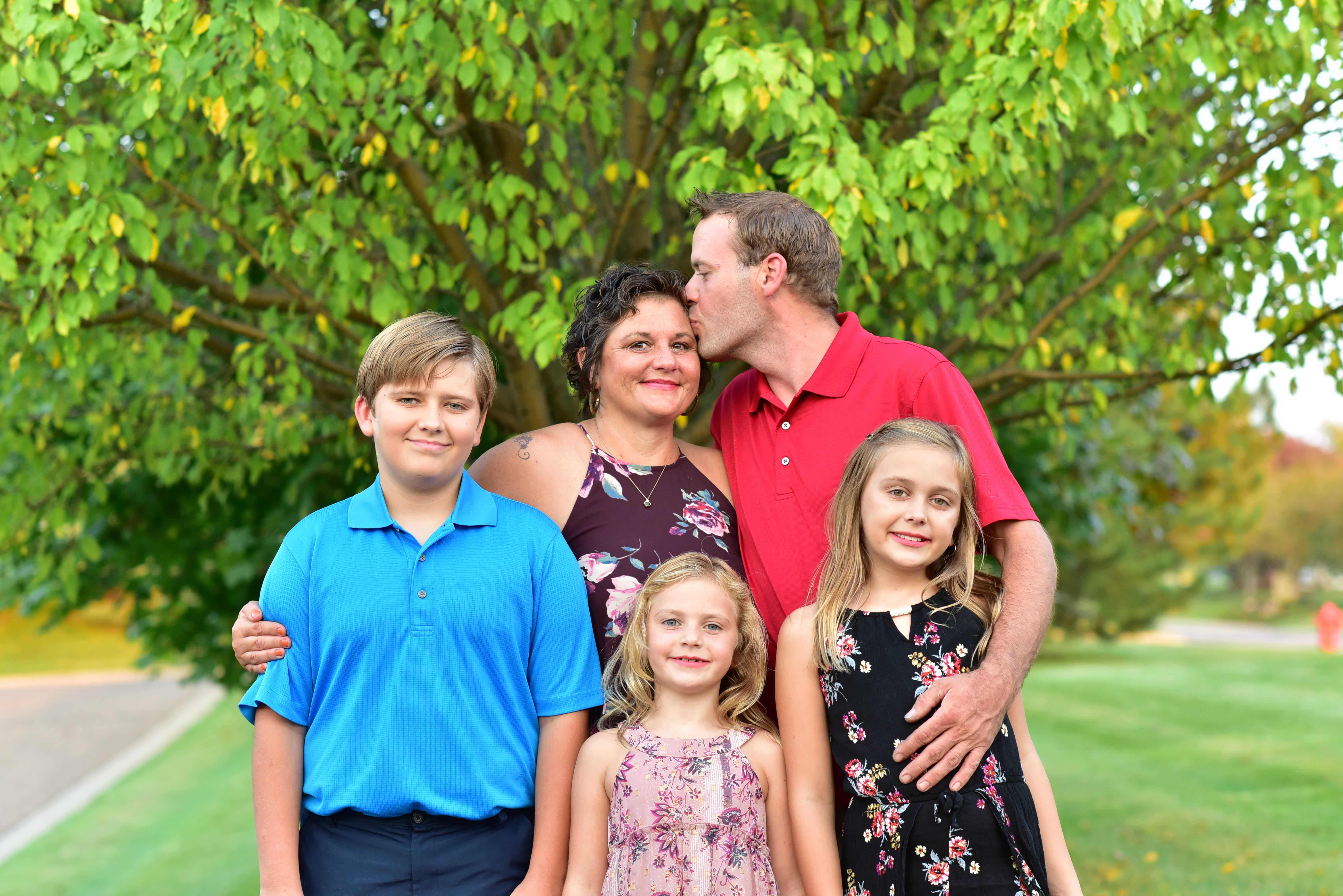 A family of five smiling in a park