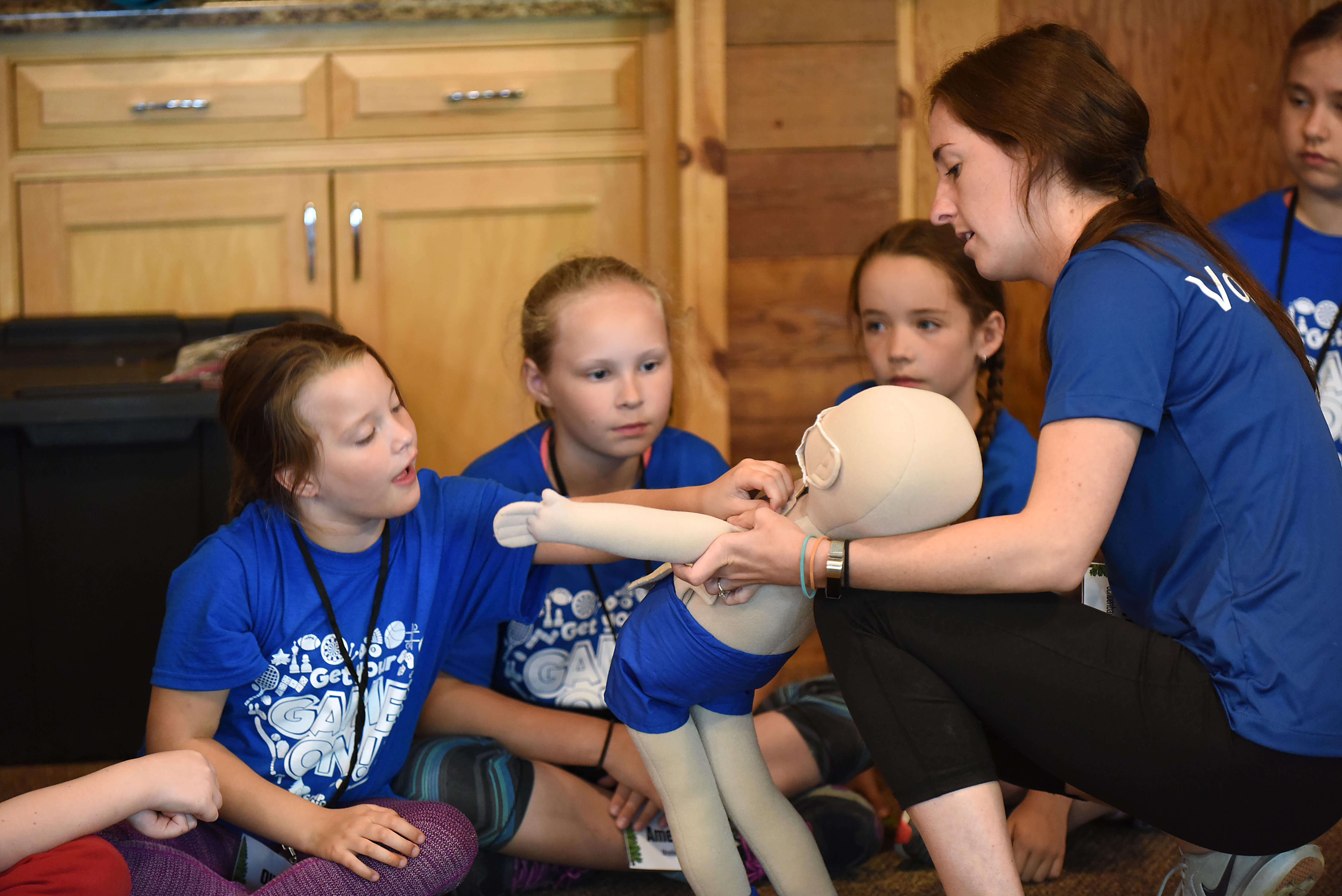 A woman showing a medical doll to a group of children.