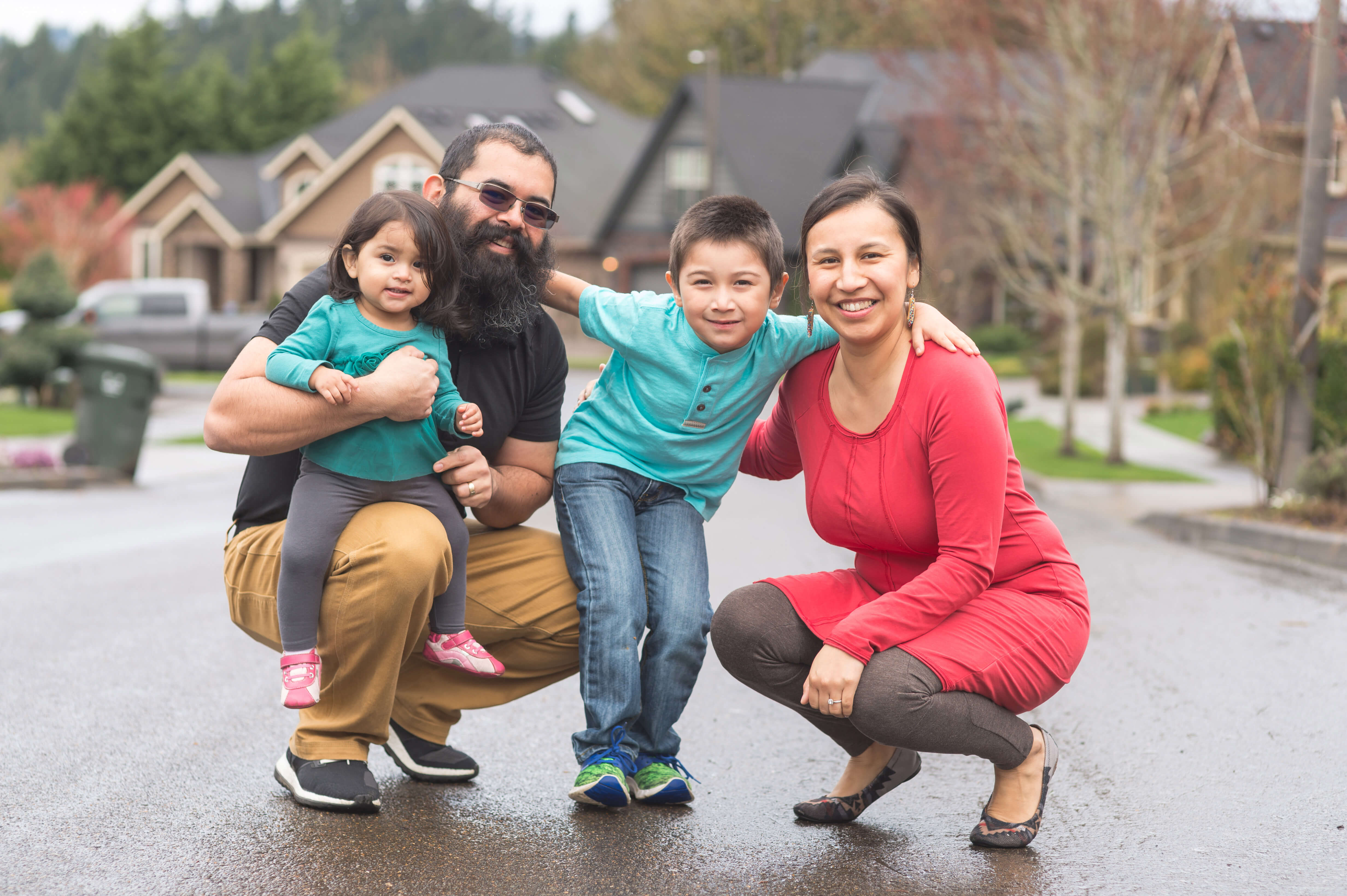 A family of four smiling in a neighborhood.