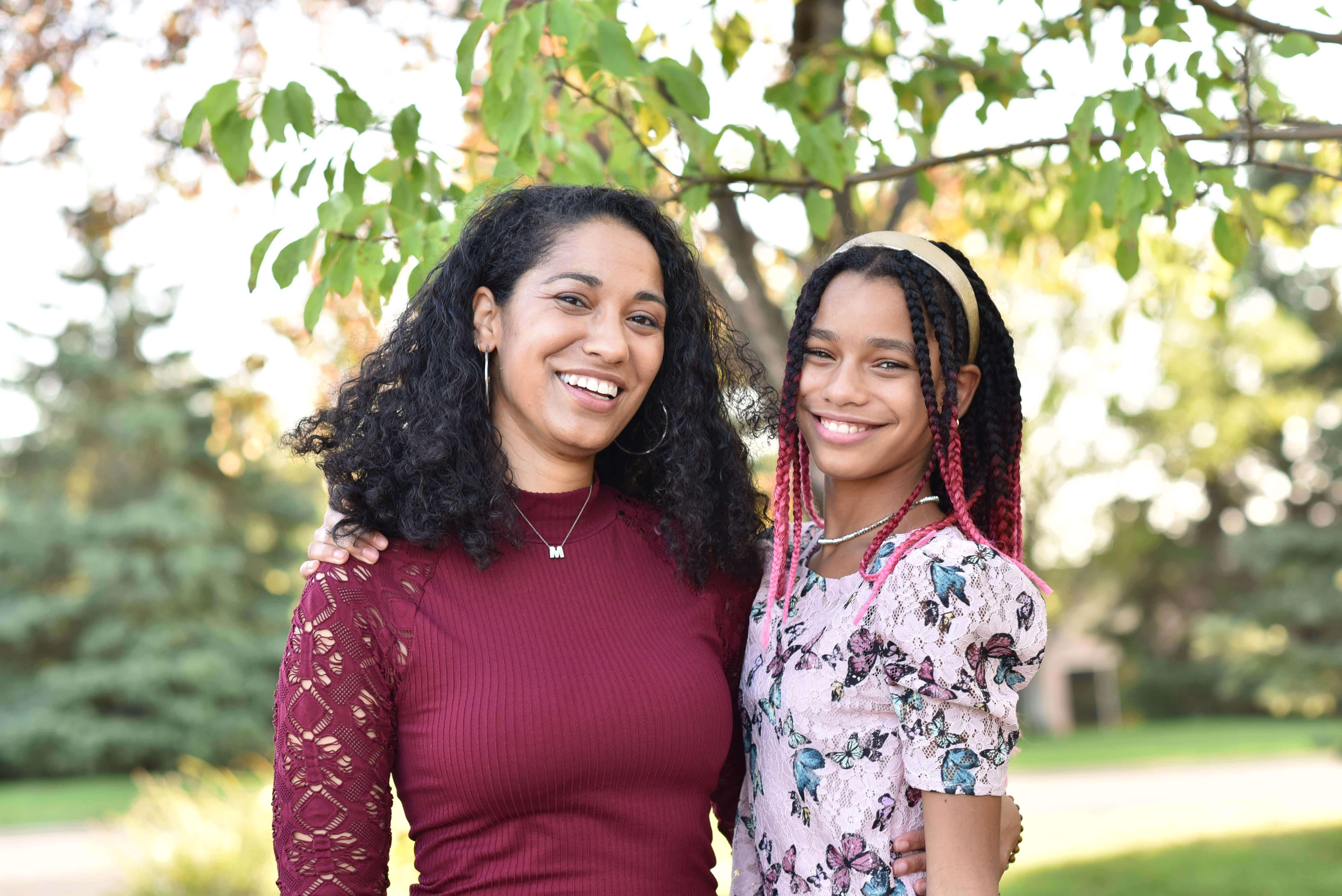 Black mom and her daughter smiling in a park.