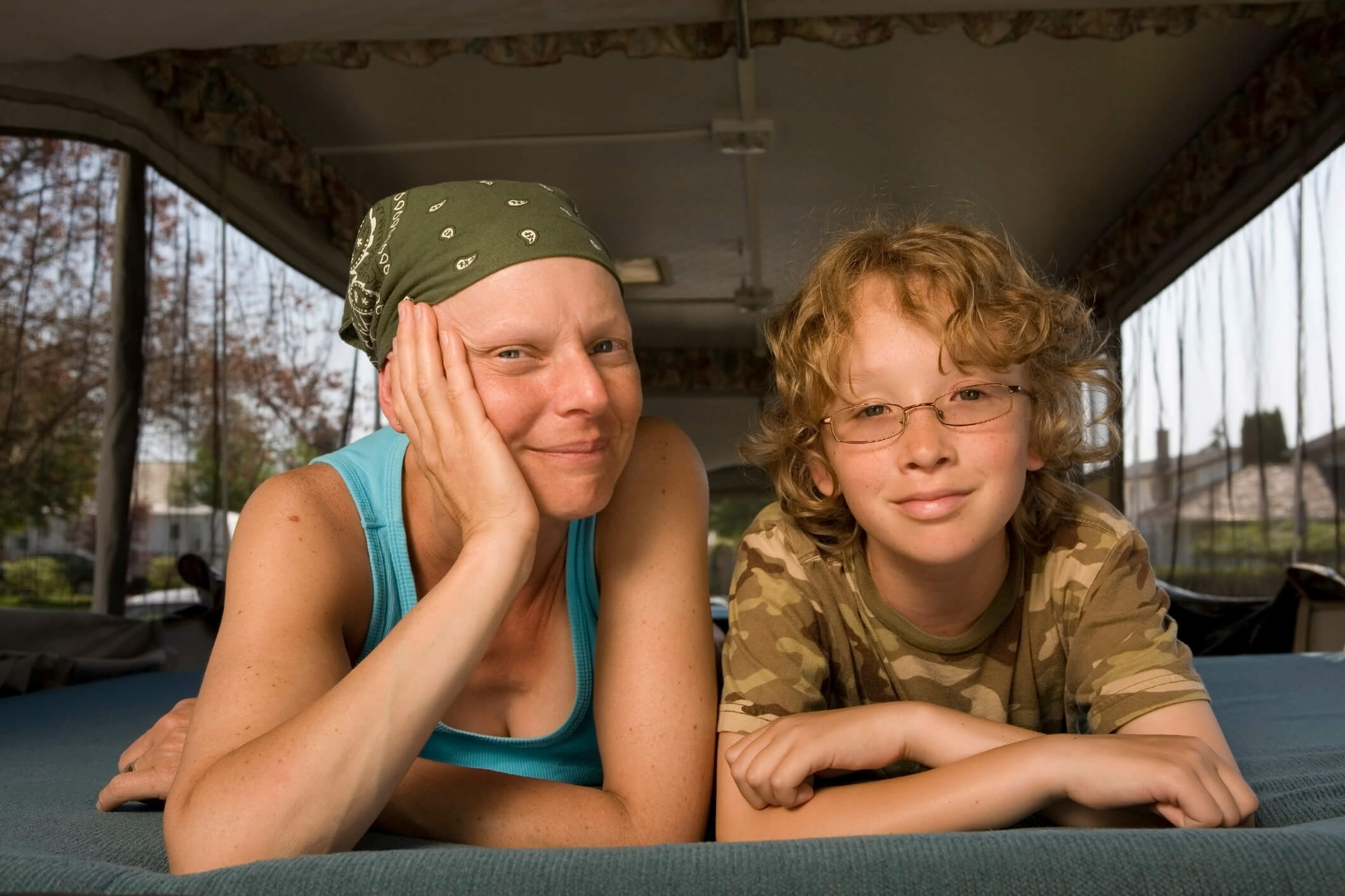 A mom with cancer and her son look into the camera.