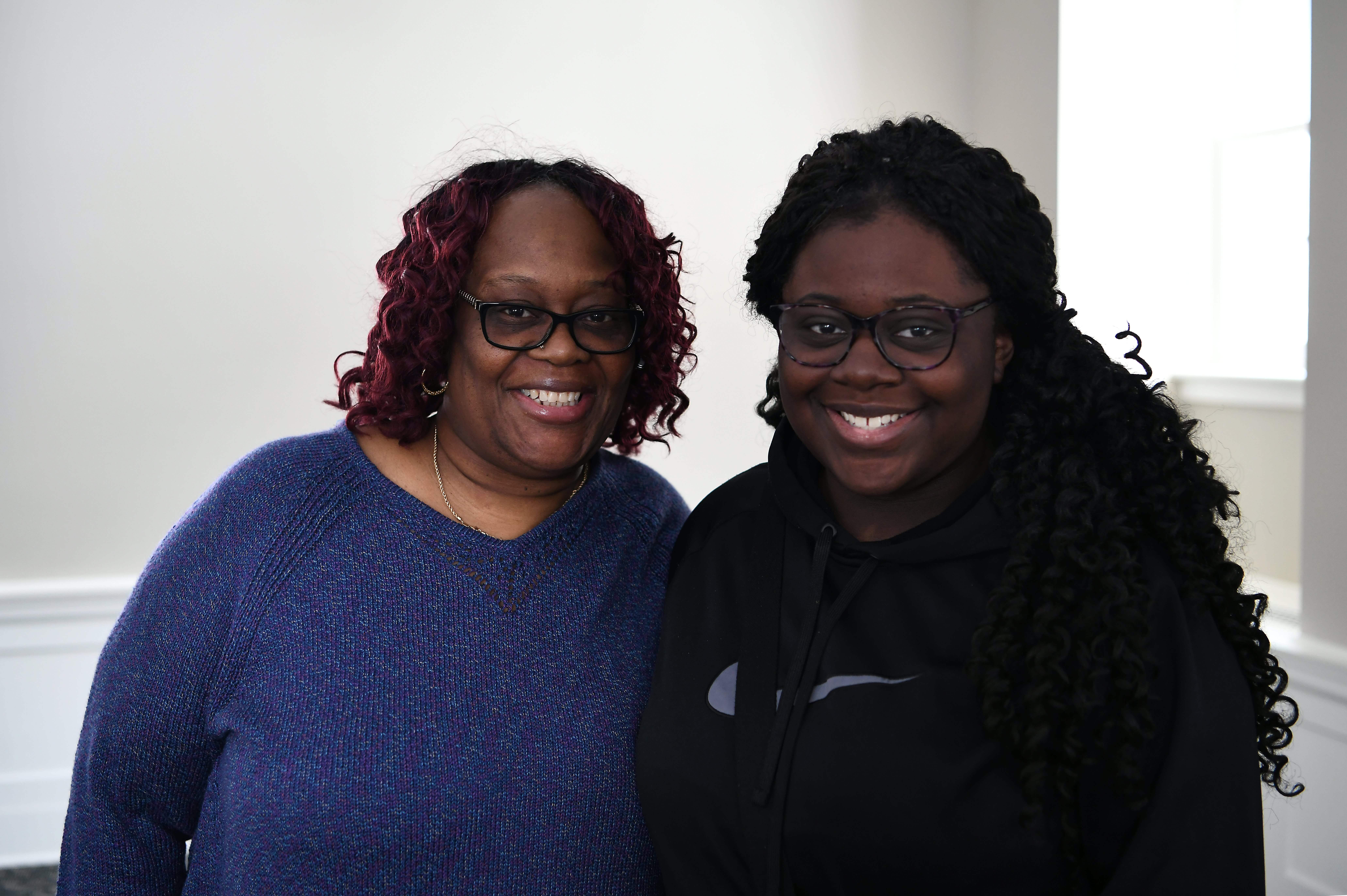 A woman and her daughter smile at the camera.