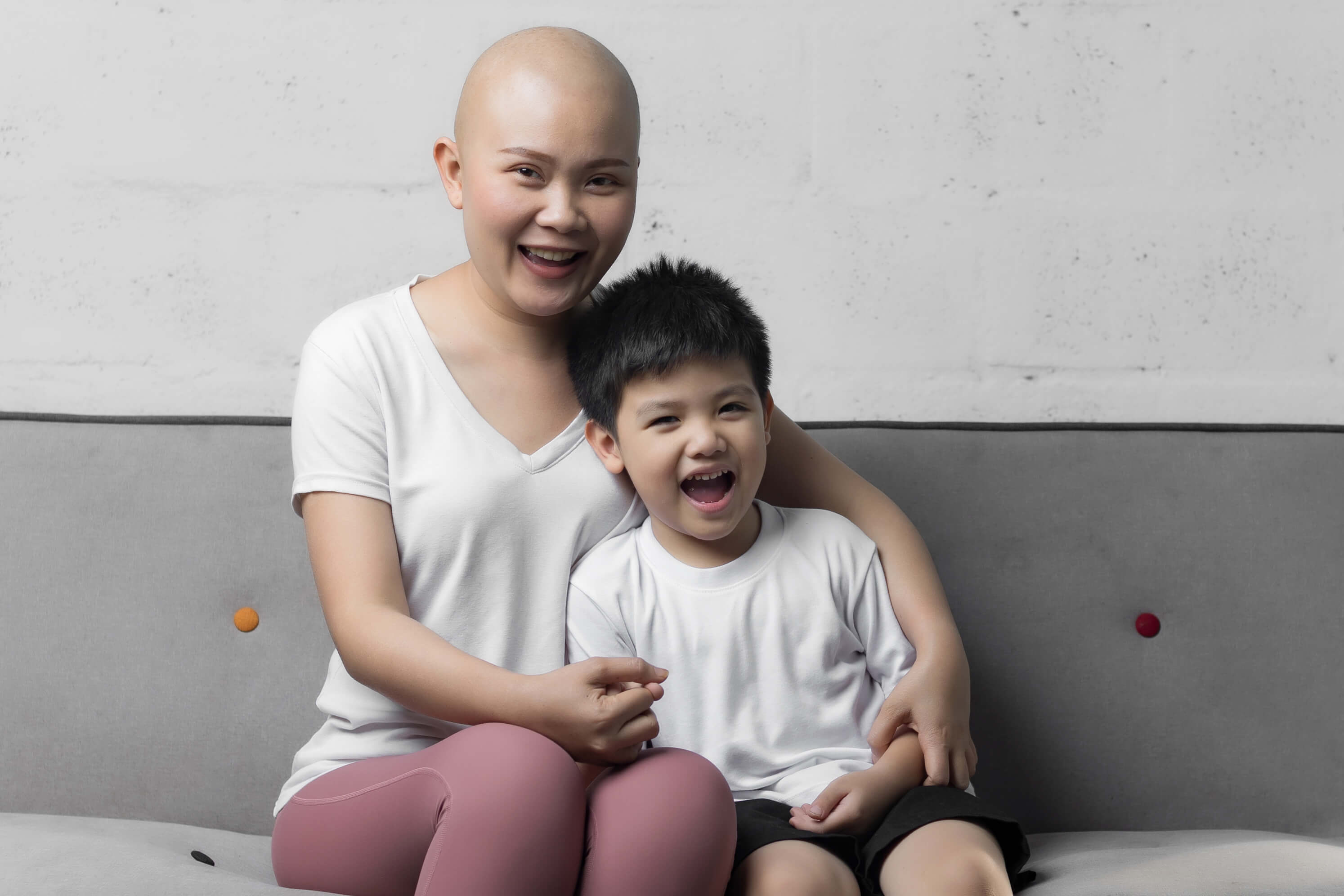 Asian mom with cancer and her son on a couch.