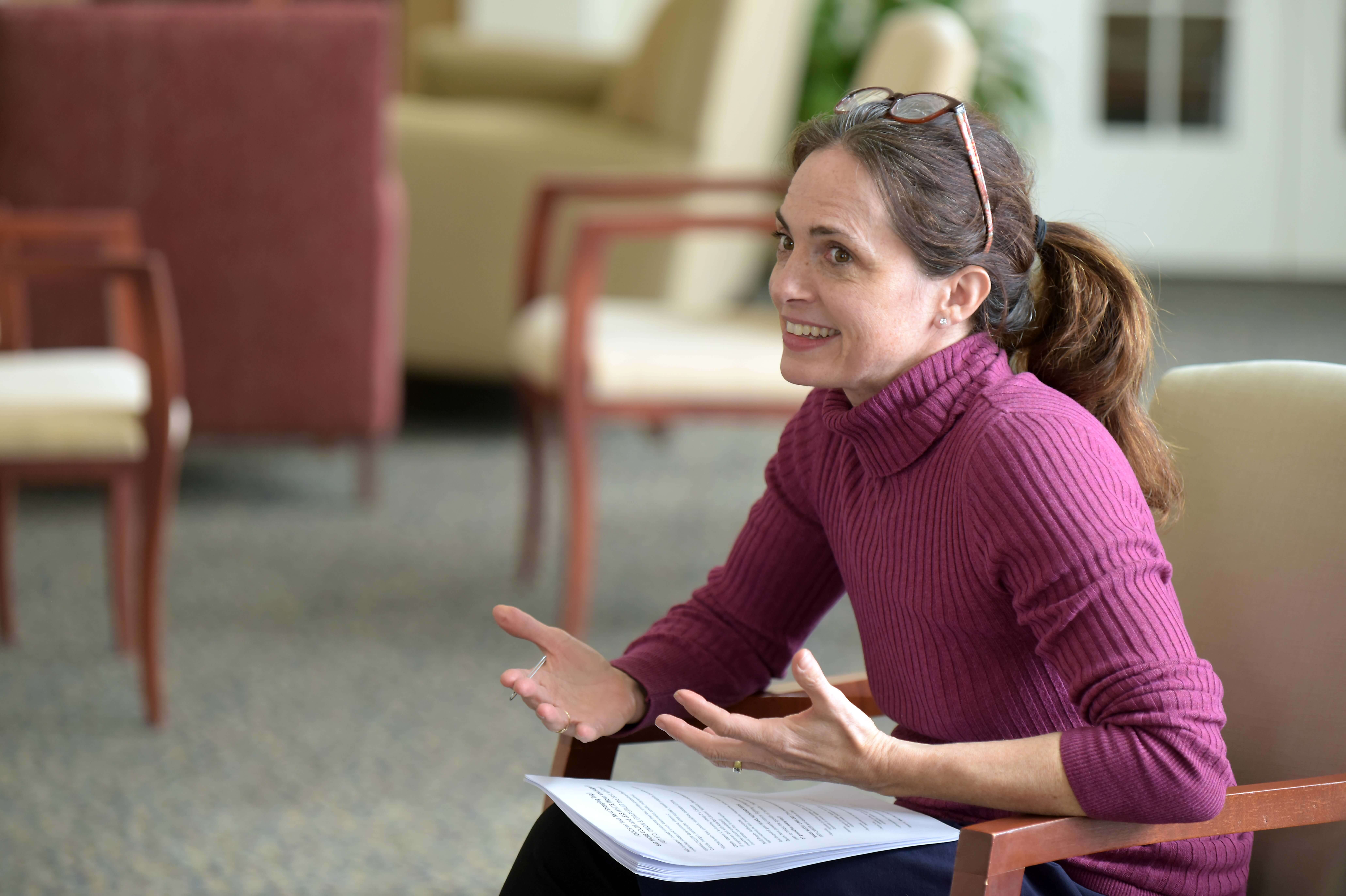 Woman in pink shirt smiling and speaking.